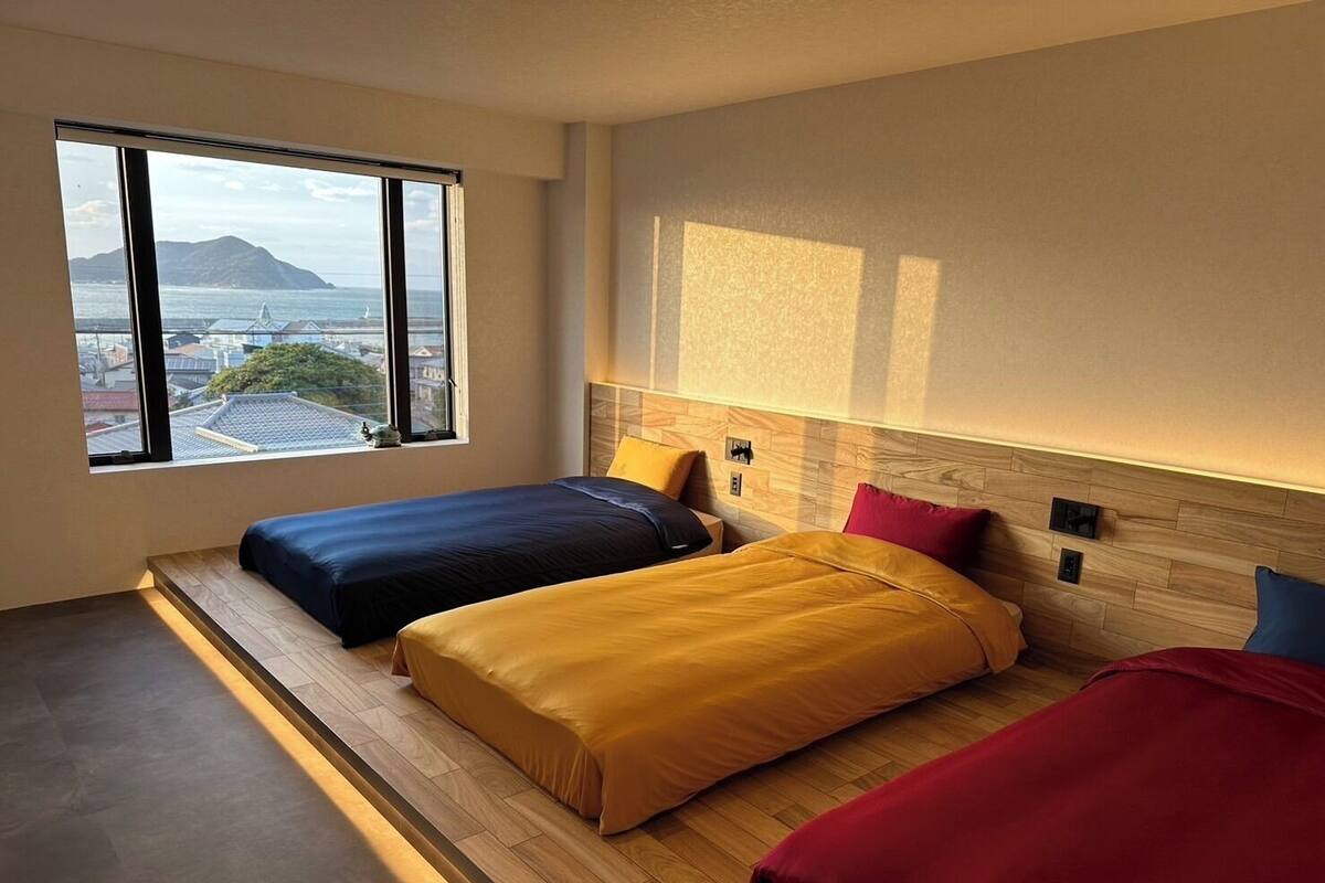 Ein modernes Hotelzimmer mit zwei Betten, einem großen Fenster und Blick auf die Stadt sowie einem Holzkopfende.