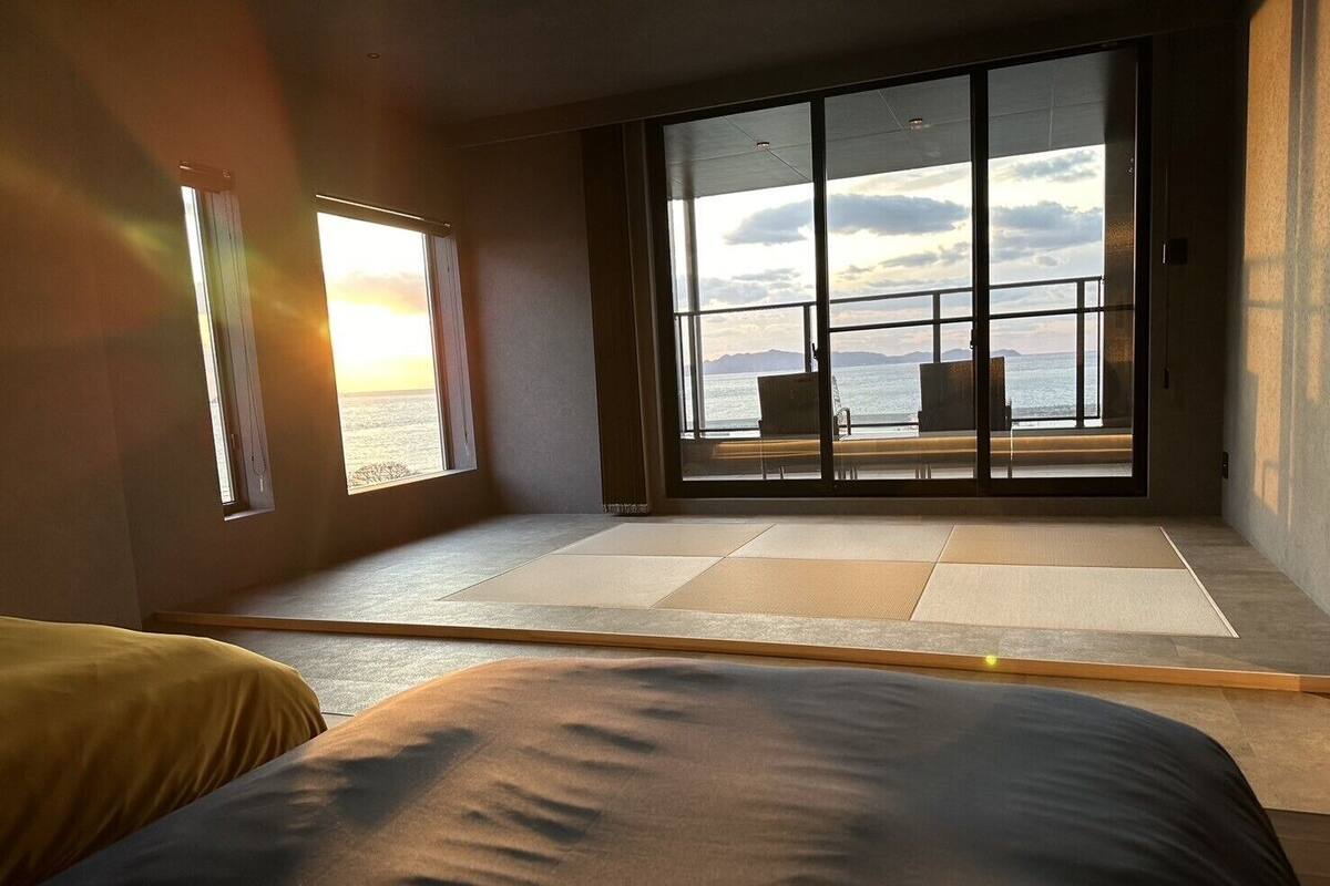 Ein Zimmer mit einer großen Schiebeglastür, die auf einen Balkon mit Meerblick führt.