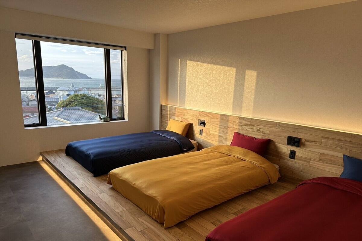 Ein modernes Hotelzimmer mit zwei Betten, einem großen Fenster mit Blick auf die Stadt und einem Holzkopfteil.