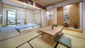 Um quarto japonês tradicional com tatames, uma mesa baixa e vista para a cidade.
