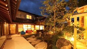 Um edifício em estilo japonês tradicional com piso de esteiras de tatame, um lago com carpas koi e um candeeiro de pedra.