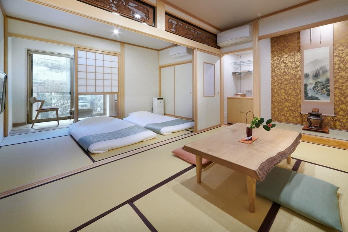 Um quarto japonês tradicional com tatames, uma mesa baixa e vista para uma paisagem coberta de neve.