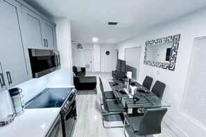 Una cucina moderna con forno a microonde, fornelli e zona pranzo con sedie e tavolo.