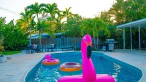 A swimming pool with inflatable flamingos and a covered patio area. - Ocean Breeze Bungalow 4BR 2BA W Pool (Hollywood)