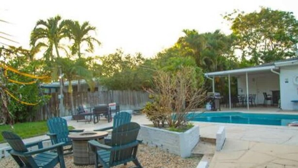 A backyard with a pool, outdoor seating, and a covered area. - Ocean Breeze Bungalow 4BR 2BA W Pool (Hollywood)