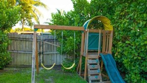 A wooden swing set with a slide in a backyard. - Ocean Breeze Bungalow 4BR 2BA W Pool (Hollywood)