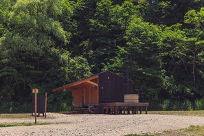 A rustic wooden cabin with a porch, a wooden deck, and a large barrel. - Earthboat Village Kurohime (Shinano)