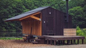 Eine Holzhütte mit einer Terrasse, einem Schornstein und einem Fass.