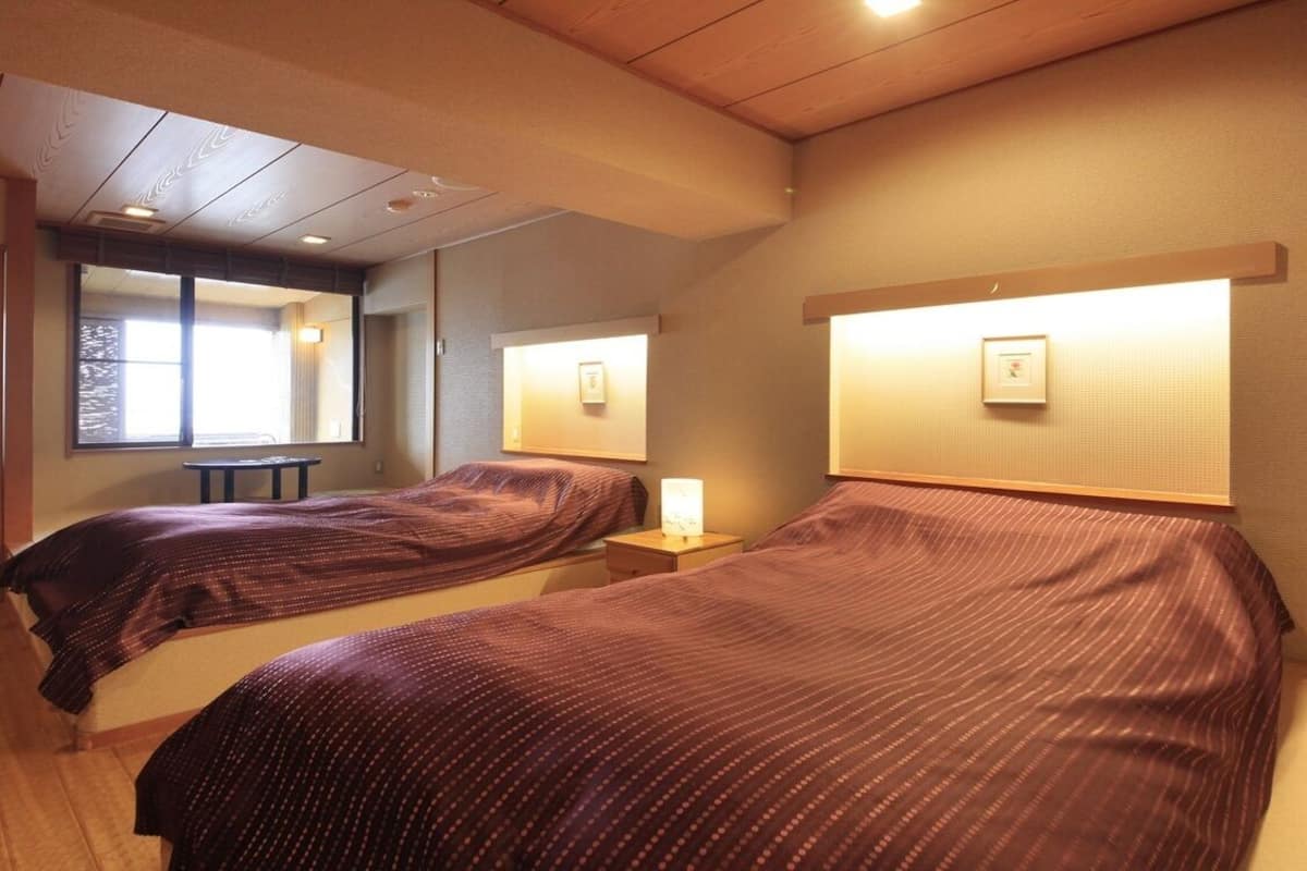Une chambre d’hôtel avec deux lits, une petite table et un miroir.