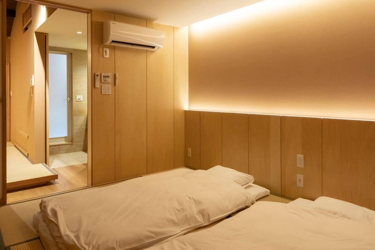 Quarto de hotel com cama, ar condicionado, porta deslizante e espelho.
