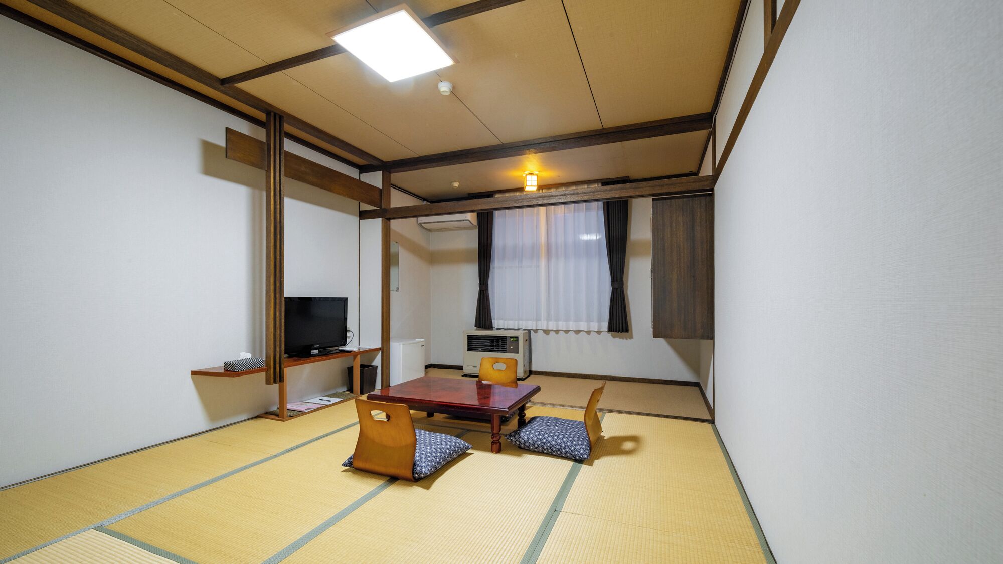 Una habitación japonesa tradicional con suelo de tatami, una mesa baja, un televisor y un calentador.