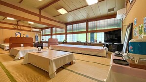A traditional Japanese inn with tatami mat flooring, multiple tatami mat rooms, a television, and a large window offering a view of the outdoors.