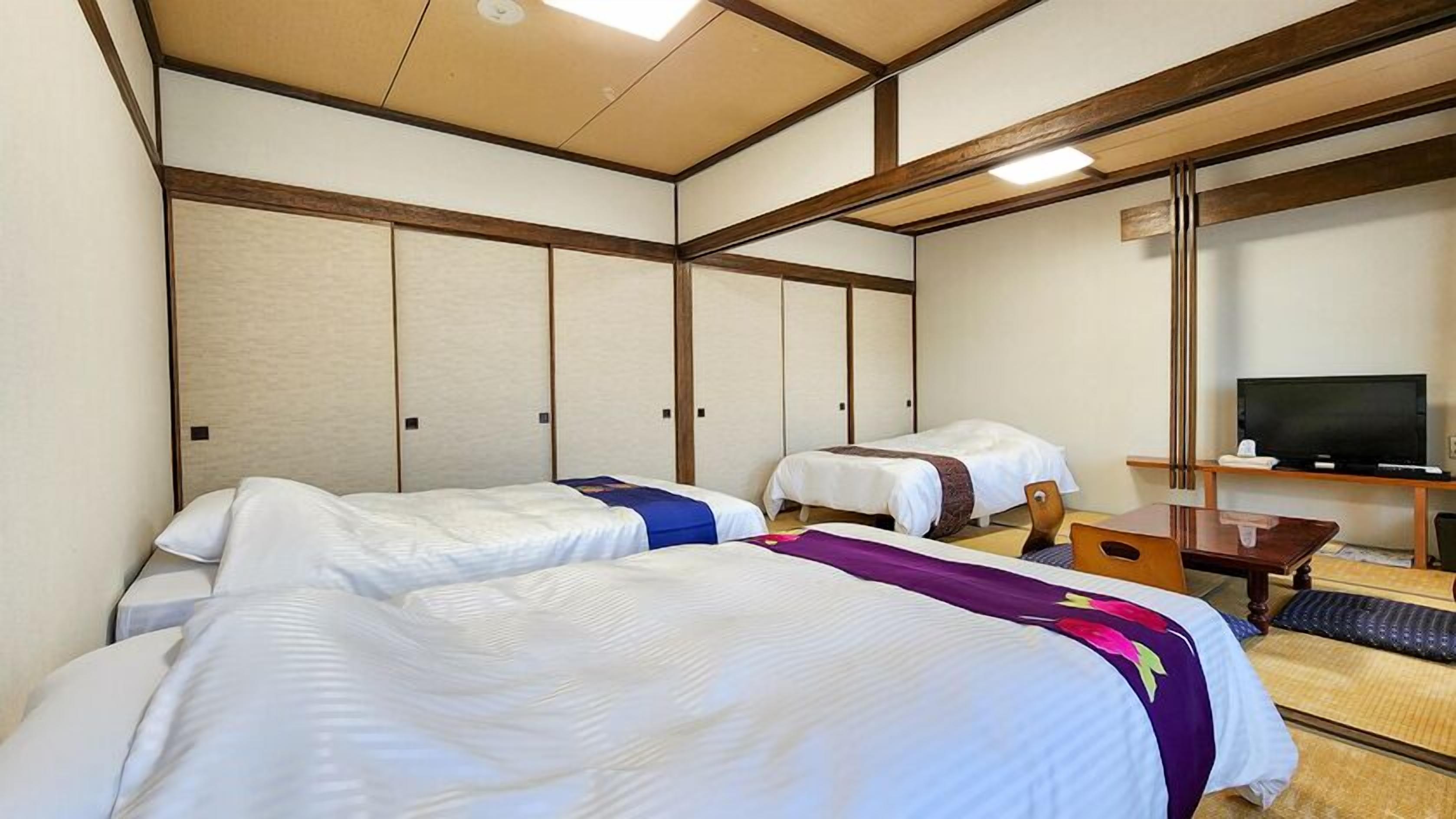 Habitación de hotel con dos camas, una televisión y un escritorio.