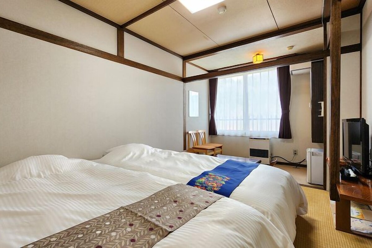 A hotel room with a large bed, a desk with a computer, and a television.