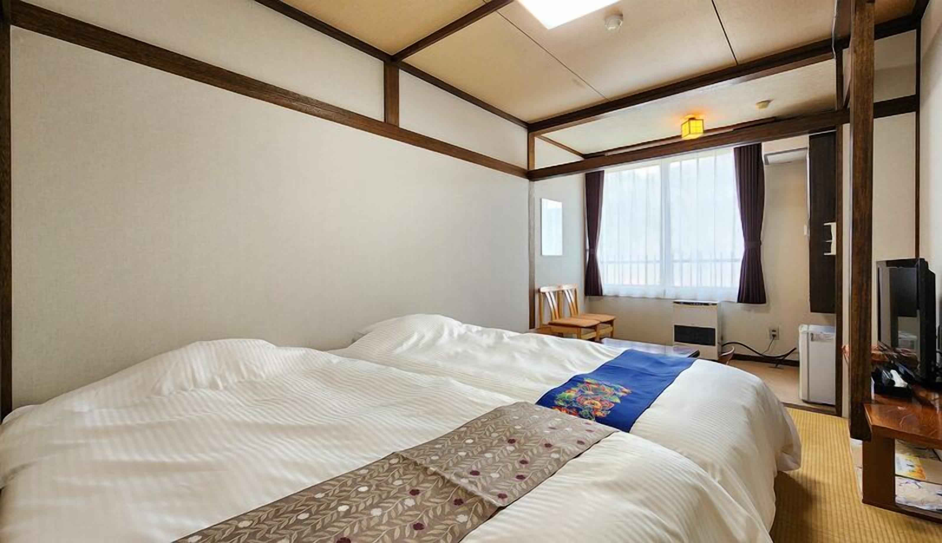 Una habitación de hotel con una cama grande, un escritorio con una computadora y una televisión.
