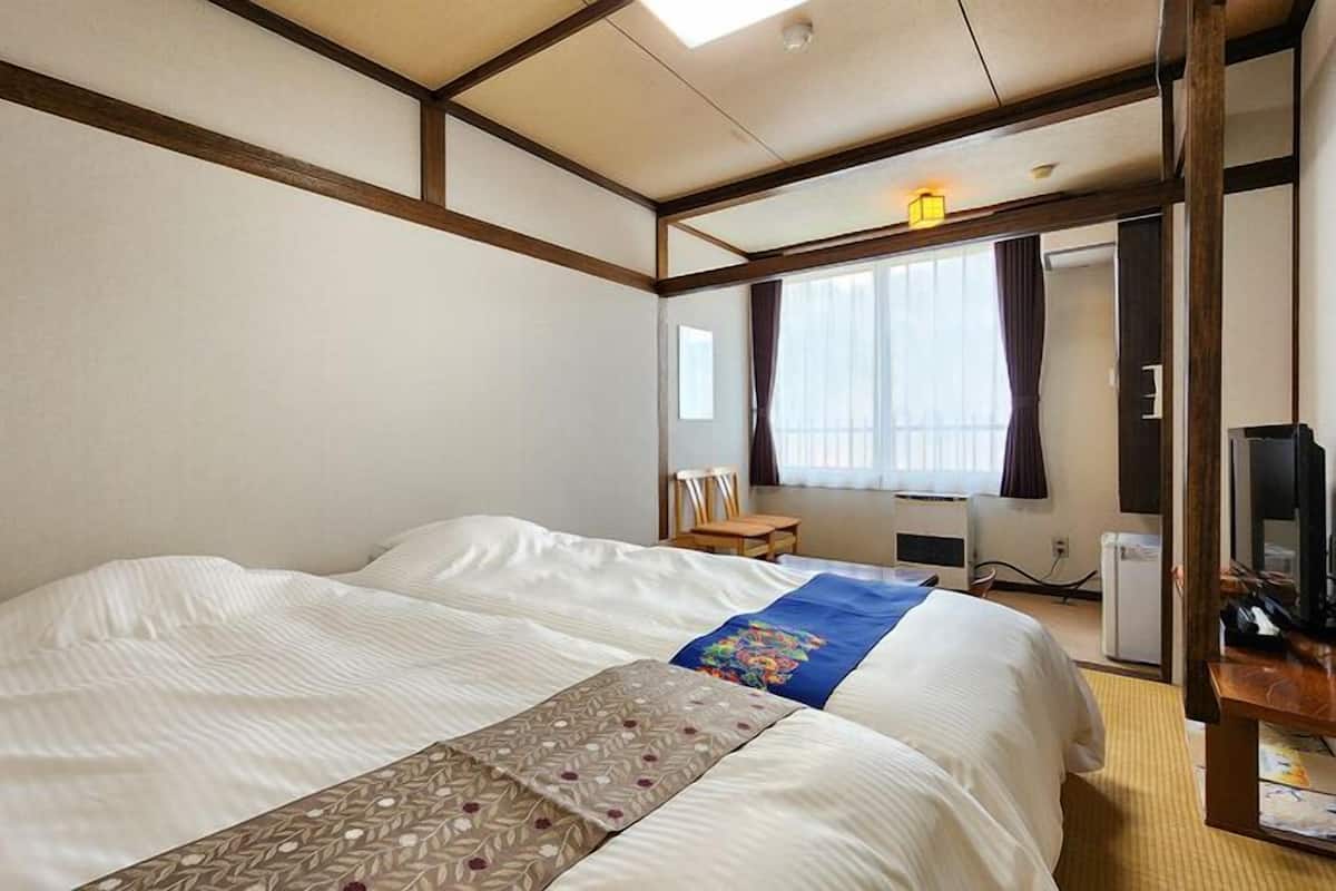 Une chambre d’hôtel avec un grand lit, un bureau avec un ordinateur et une télévision.