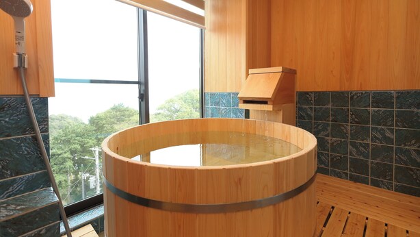 A wooden bathtub with a view of trees outside.