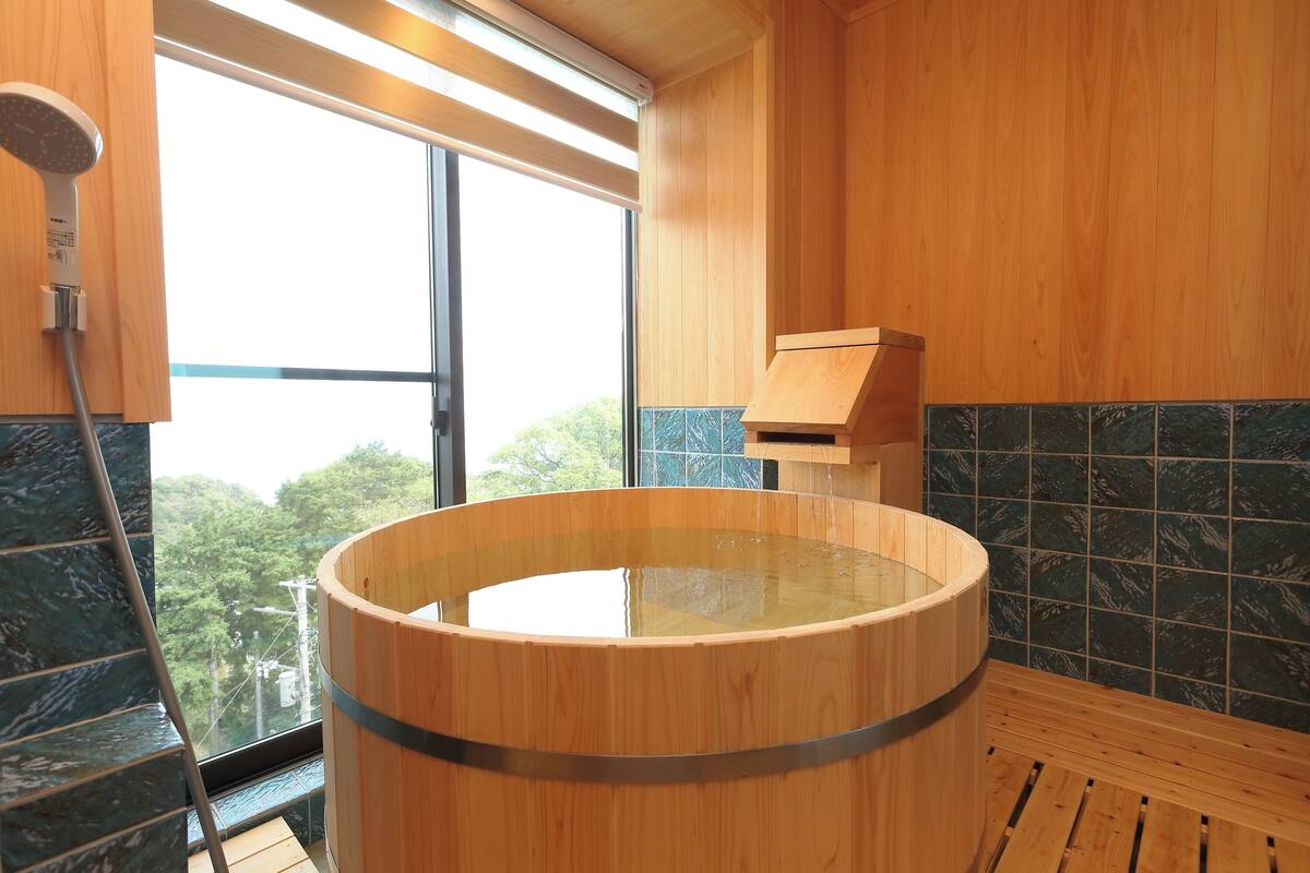 A wooden bathtub with a view of trees outside.