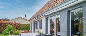 Ein Haus mit Terrasse, Schiebetür und Schornstein.