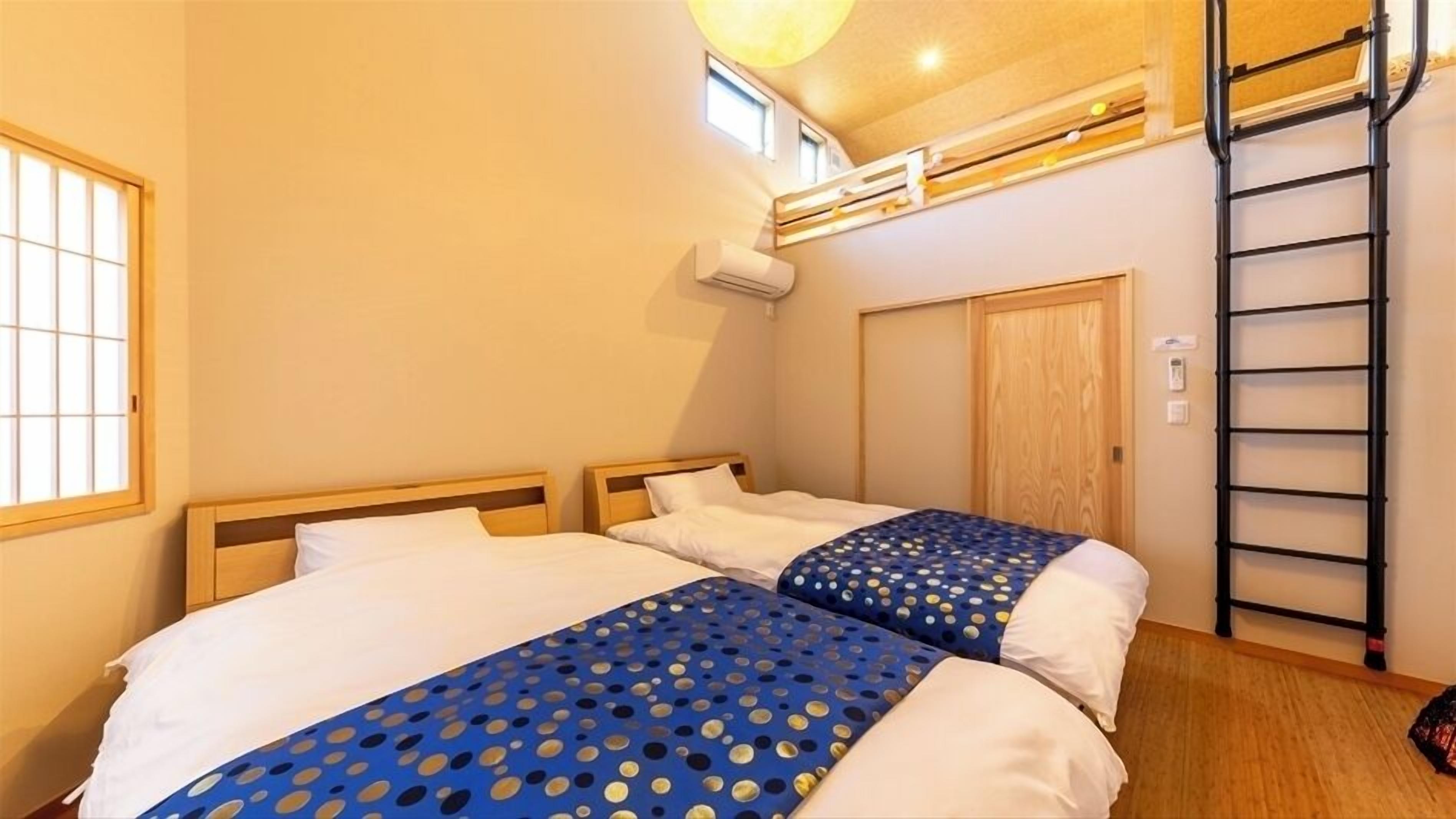 A bedroom with two beds, a ladder, a window, and an air conditioning unit.