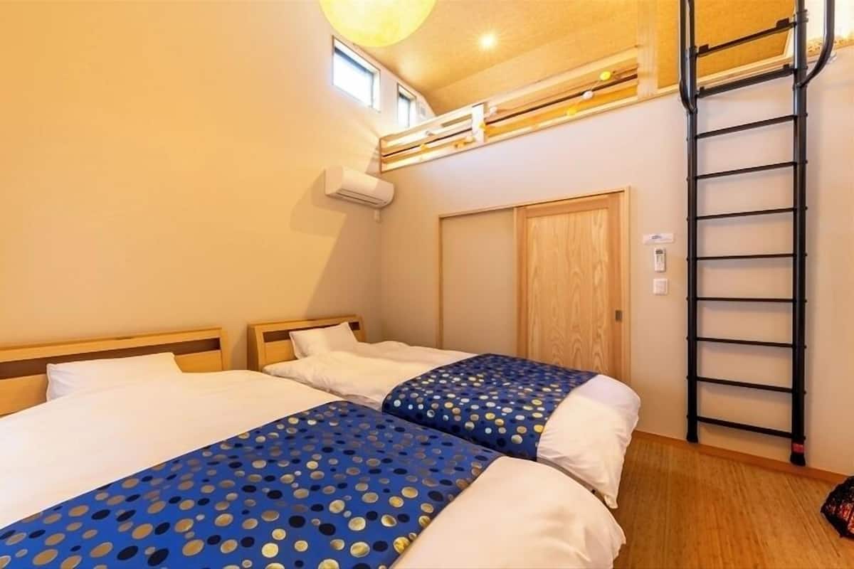 Ein Schlafzimmer mit zwei Betten, einer Leiter, einem Fenster und einer Klimaanlage.