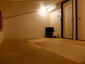 Een kamer met tatami matten, een televisie en een schuifdeur.