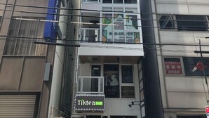 A multi-story building with a visible storefront on the ground floor, a sign for 'Tiktea,' and several other signs with Japanese text. - Illi Nakano (Tokyo)