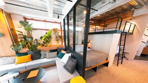 A modern interior with a loft bed, a sofa, a dining table, and various plants. - Illi Nakano (Tokyo)