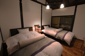 Ein Hotelzimmer mit zwei Betten, Holzboden und einem großen Fenster.