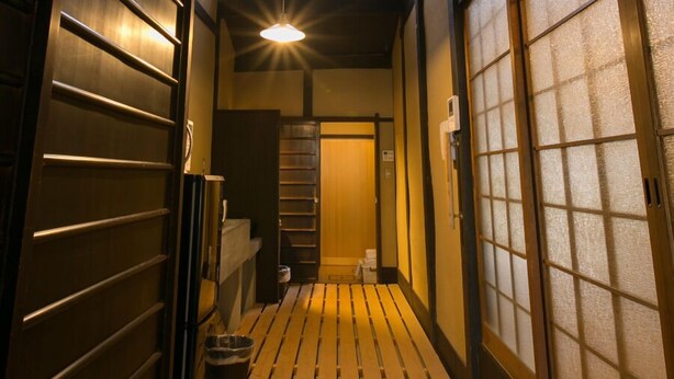 A narrow hallway with wooden flooring, a trash bin, and traditional sliding doors. - Demizu Machiya (Kyoto)