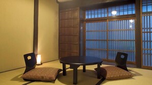 A tatami mat room with a round table and two chairs, a shoji screen, and a wall-mounted air conditioner. - Demizu Machiya (Kyoto)