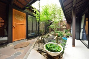 A traditional Japanese-style entrance with a wooden door, a stone pathway, and a small rock garden. - Takeya Kitano Honkan (Kyoto)