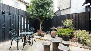 A patio area with a round table and chairs, surrounded by potted plants and a decorative stone feature. - Kyo no Yume (Kyoto)