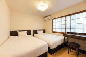 A hotel room with two beds, a desk, a chair, a window with a view, and an air conditioning unit. - Kyonoyume (Kyoto)