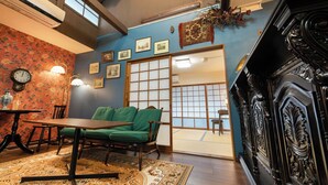 A traditional Japanese-style room with tatami flooring, a low table, green cushions, a shoji screen door, and a black stove. - Kyonoyume (Kyoto)