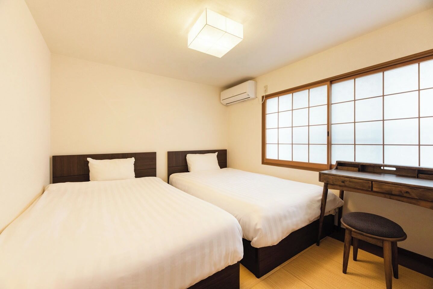 Ein Hotelzimmer mit zwei Betten, einem Schreibtisch und einem Fenster mit Blick.