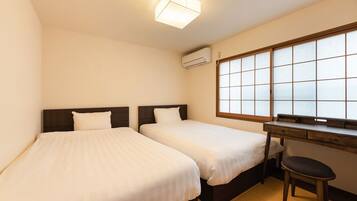 A hotel room with two beds, a desk, a chair, and a large window with a view.
