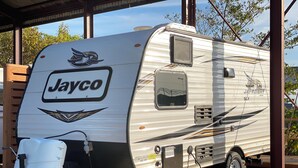 Uma RV Jayco com área frontal coberta, uma janela lateral e um pequeno compartimento de armazenamento.