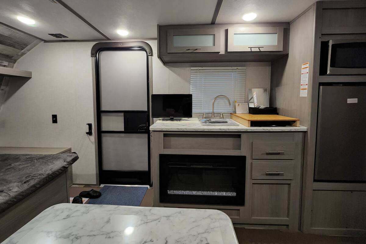 A compact RV kitchen with a built-in oven, a microwave, and a refrigerator.