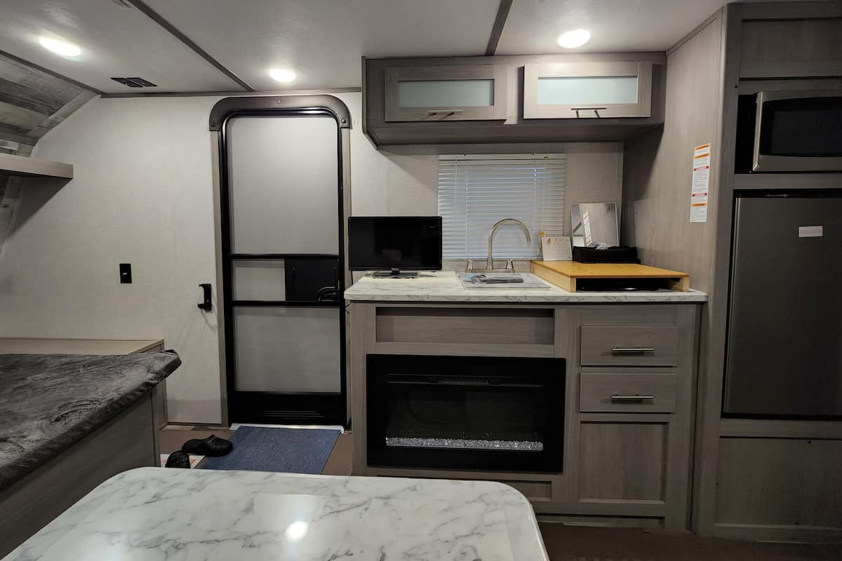 A compact RV kitchen with a built-in oven, a microwave, and a refrigerator.