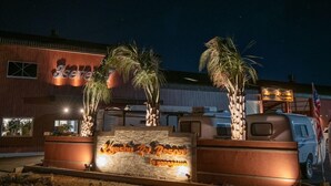 Señalización para 'Kyushu Resort', con palmeras y un vehículo estacionado al frente.