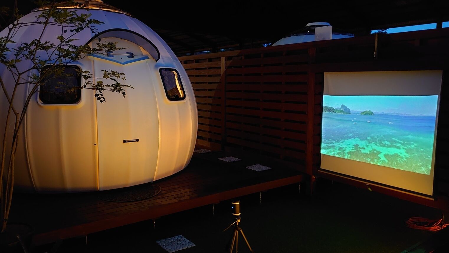 A futuristic capsule-like structure with a large screen displaying a scenic view.