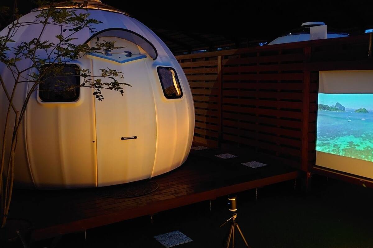 A futuristic capsule-like structure with a large screen displaying a scenic view.