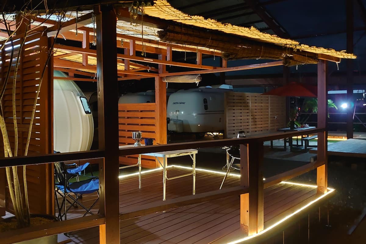 A wooden RV with a covered porch and a dining area.