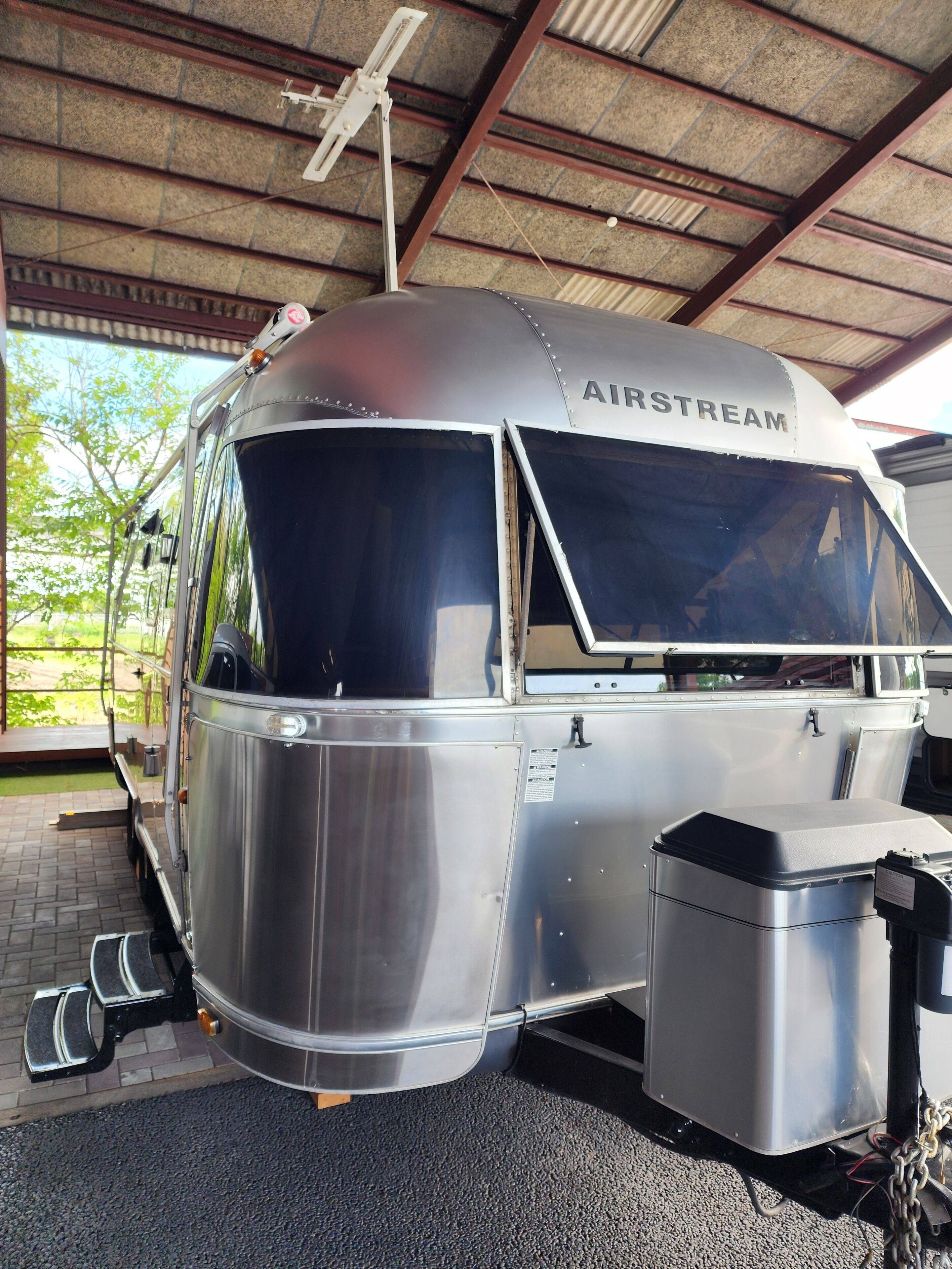 A stationary, metallic vehicle with 'AIRSTREAM' written on the side, equipped with steps and a storage compartment.