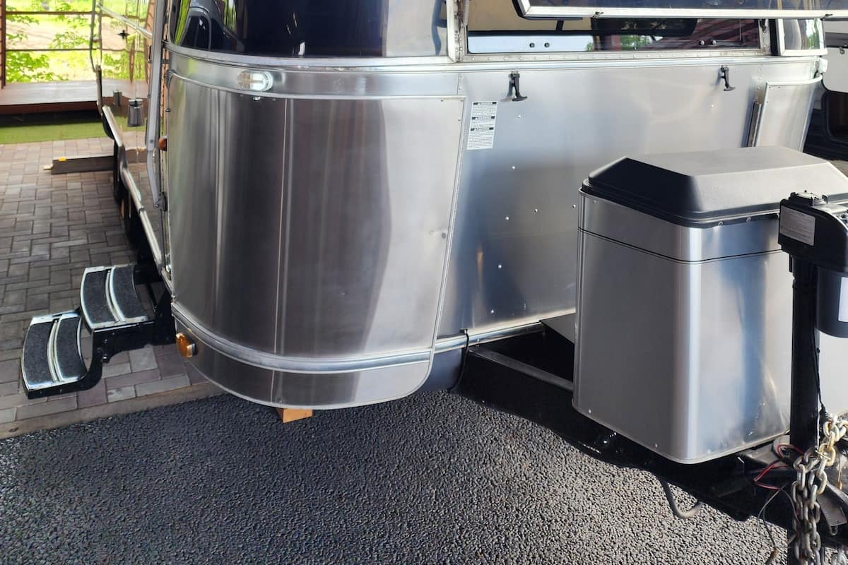A stationary, metallic vehicle with 'AIRSTREAM' written on the side, equipped with steps and a storage compartment.