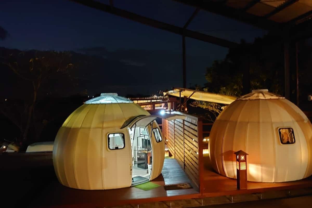 Two spherical structures with entryways, a small staircase, and a wooden bench.