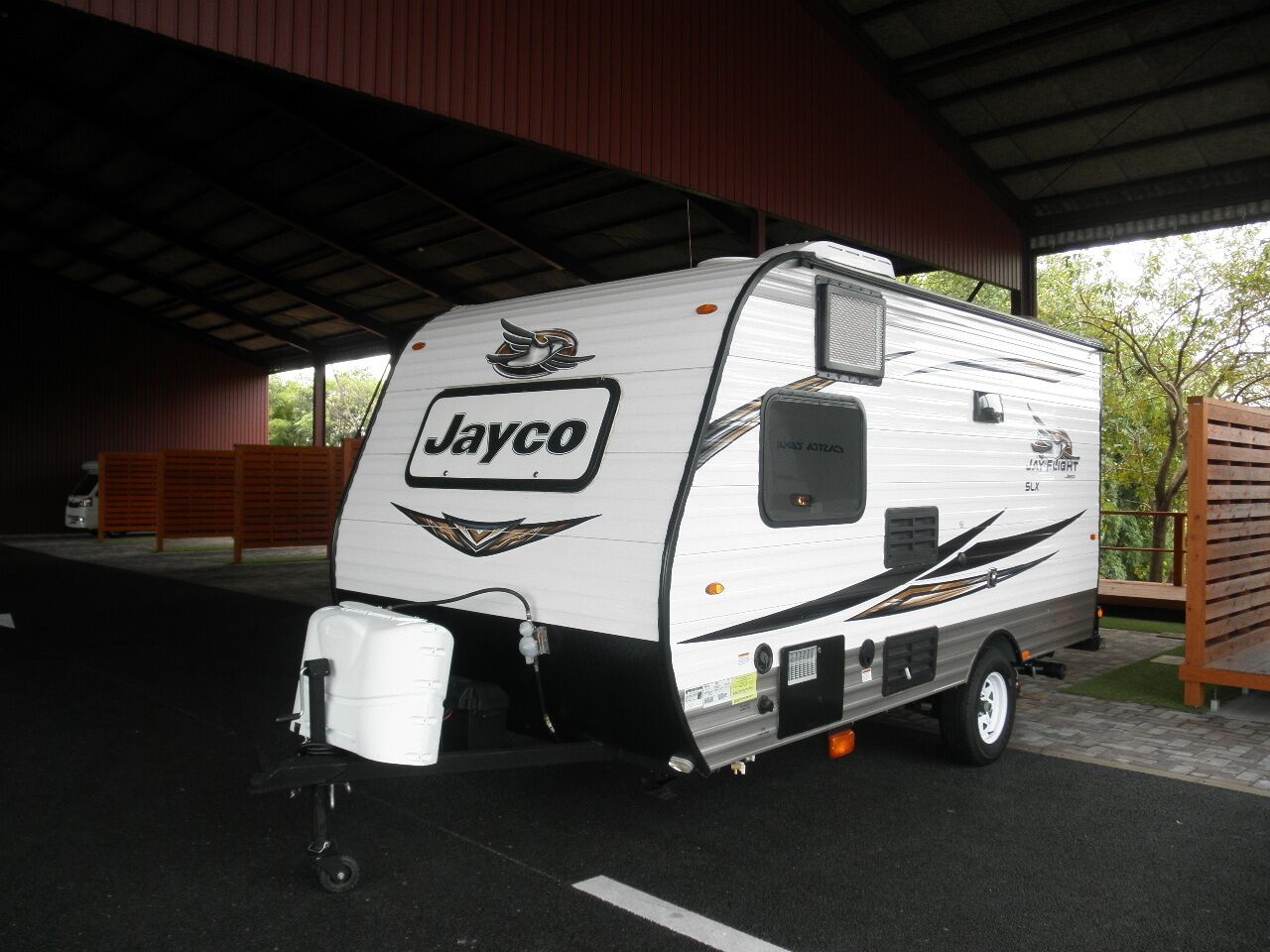 A Jayco RV parked under a covered area with a metal roof.