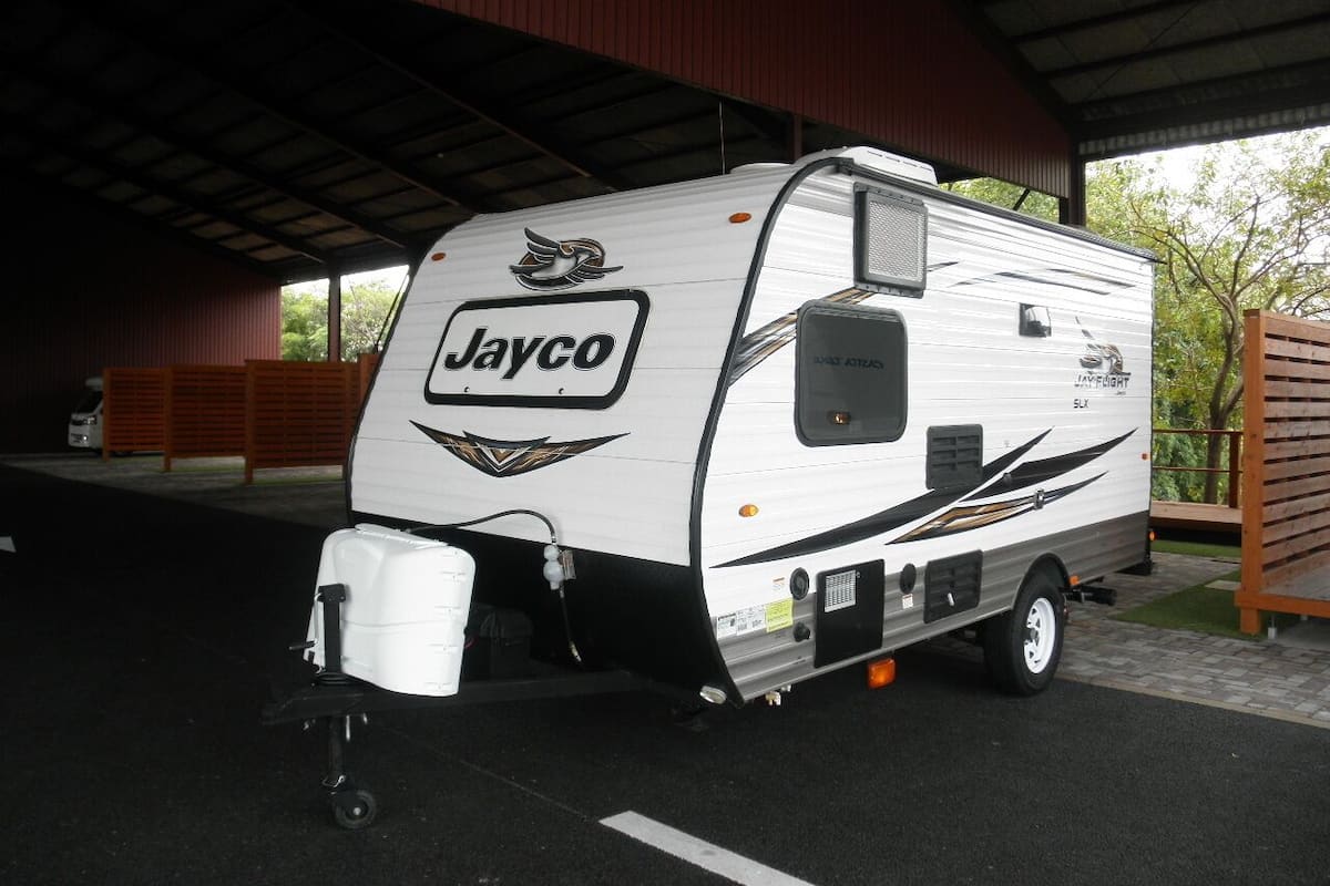 A Jayco RV parked under a covered area with a metal roof.