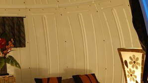 Una habitación acogedora con cama, almohadas, una lámpara, una planta y una pared con textura.